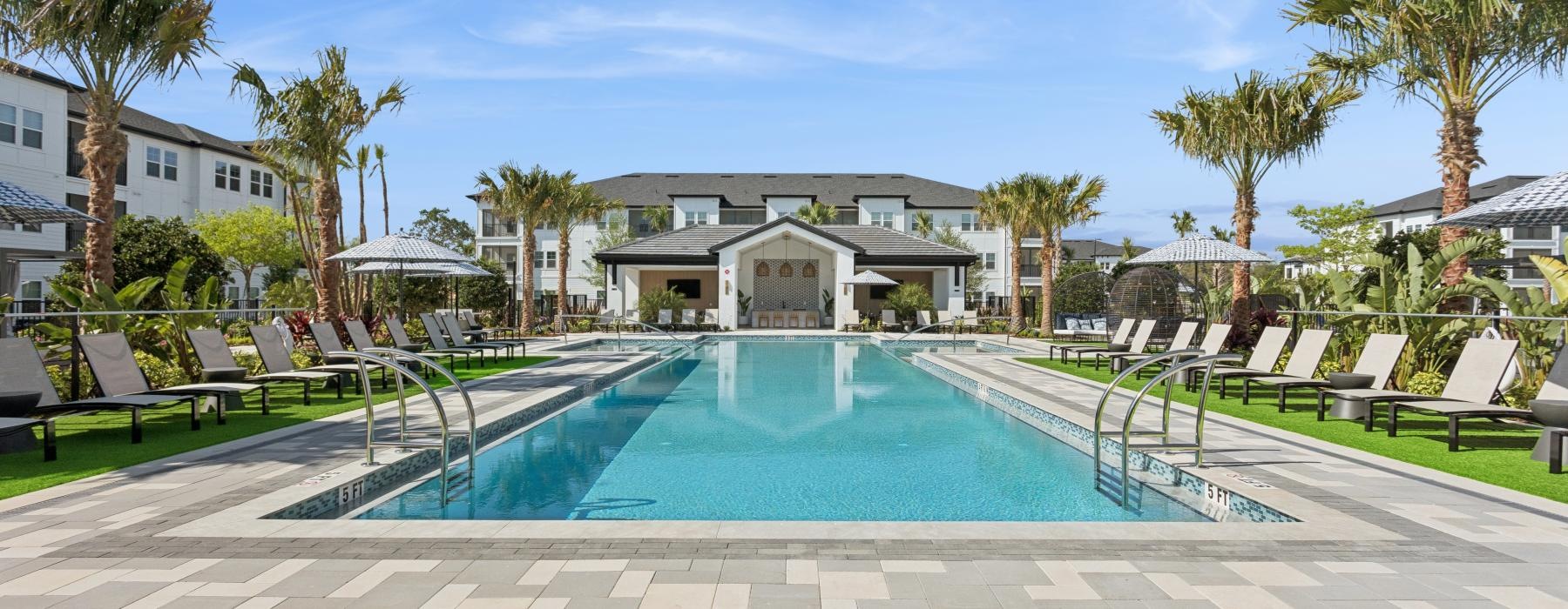a swimming pool with palm trees and a building in the background