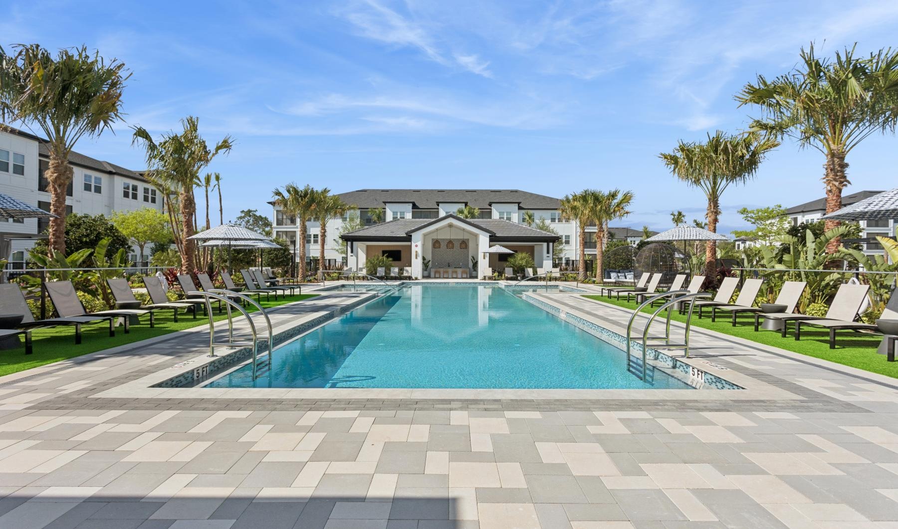 a swimming pool with palm trees and a building in the background